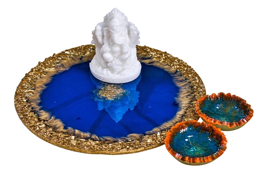 Blue festive platter with gold-toned rim, a white Ganesha idol and two small bowls